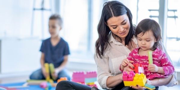 childcare provider with an infant on her lap