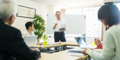 photo of professor standing before engaged students at tables
