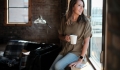 Young women gazing out of her loft window with coffee in hand - Quad Cities